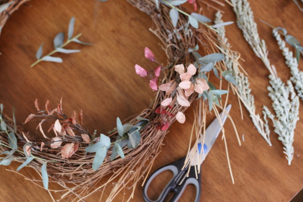 scissors and wreath and greenery laying on wood table