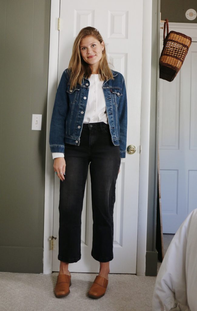 woman wearing denim jacket and thrifted top and jeans in front of closet