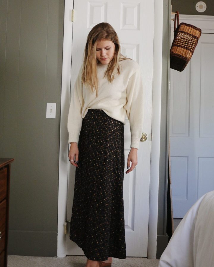 woman in cream sweater and skirt in front of closet