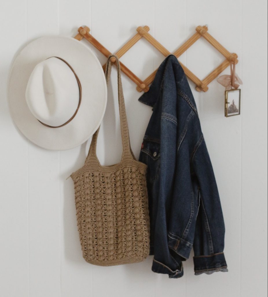hat, purse, denim jacket, and photo hanging on wood accordion rack