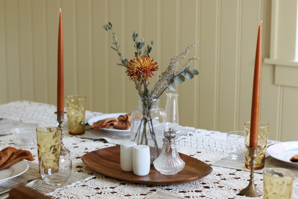 thanksgiving table decorated with orange candlestick and dried flowers