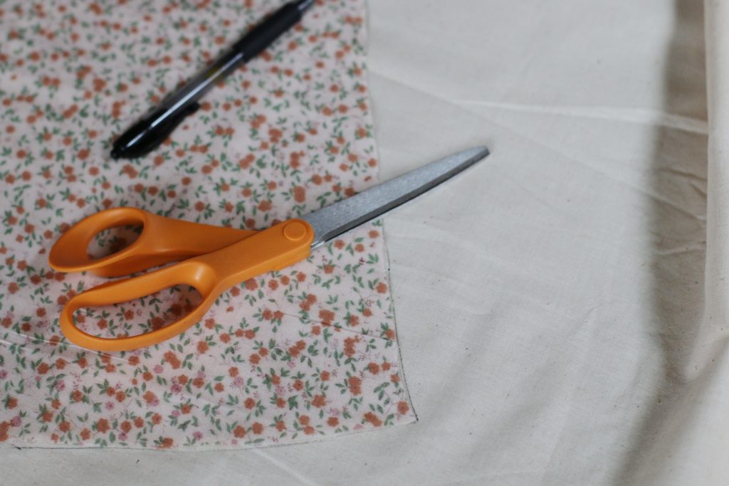 scissors and pin laying on fabric