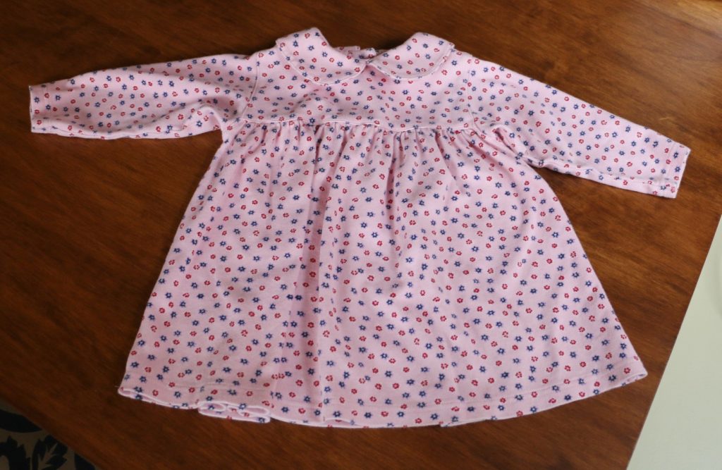 pink baby dress laying on wood table