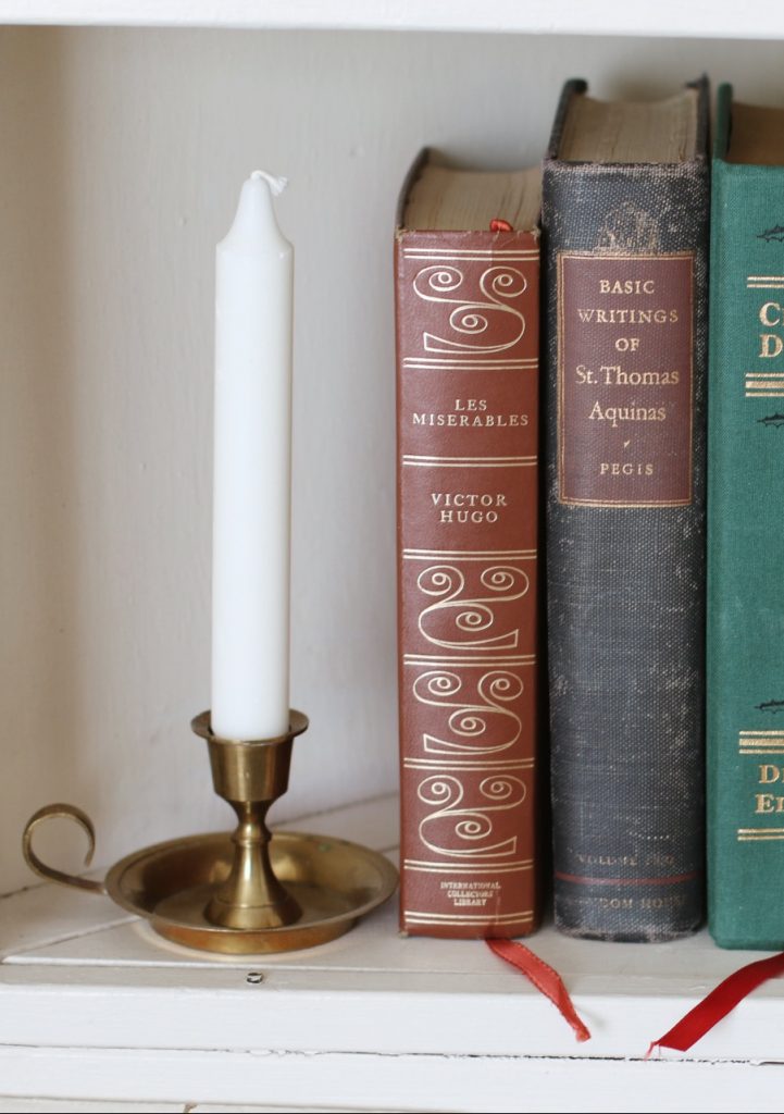 candlestick, vintage books and Christmas tree on shelf
