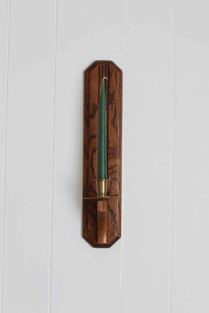 wood and brass candle sconce with green candle