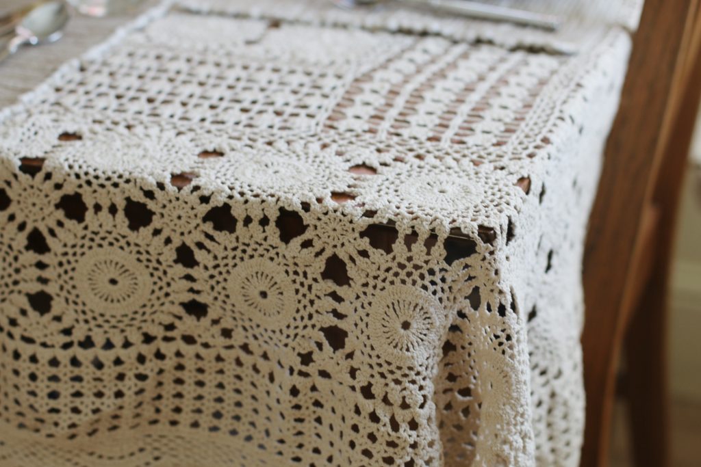 vintage crocheted tablecloth on wood table