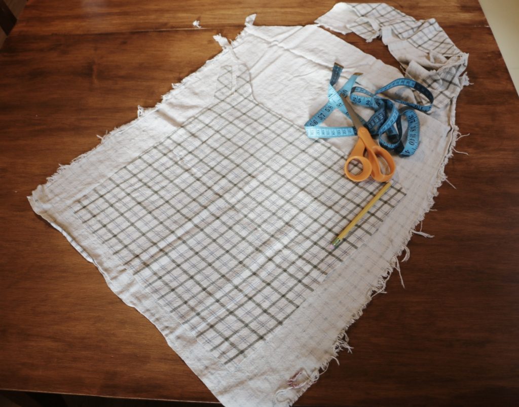 fabric cut laying on wood table with scissors and measuring tape