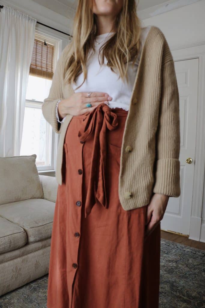 pregnant woman wearing orange skirt, white top and beige sweater
