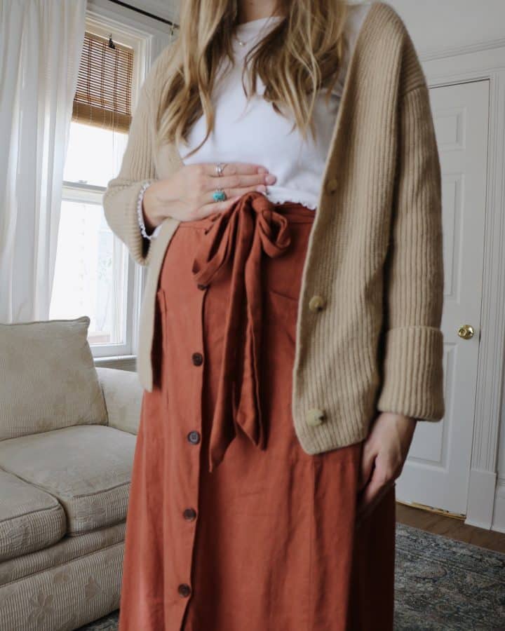 pregnant woman wearing orange skirt, white top and beige sweater