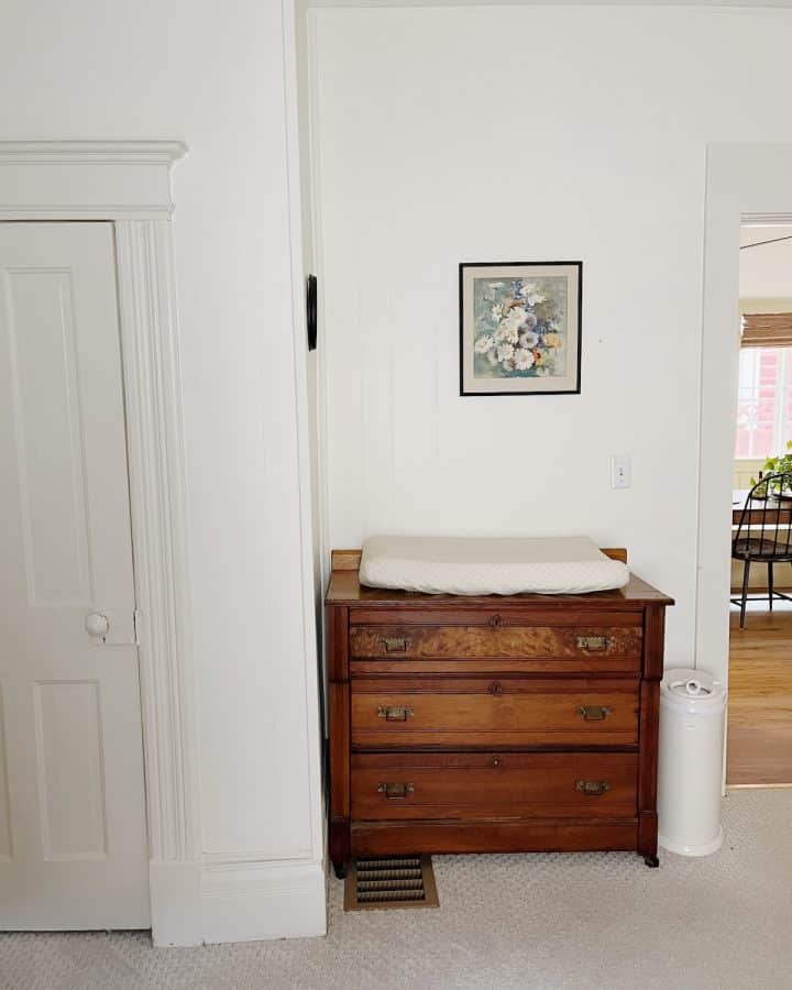 changing pad on wood dresser with floral art print hanging above