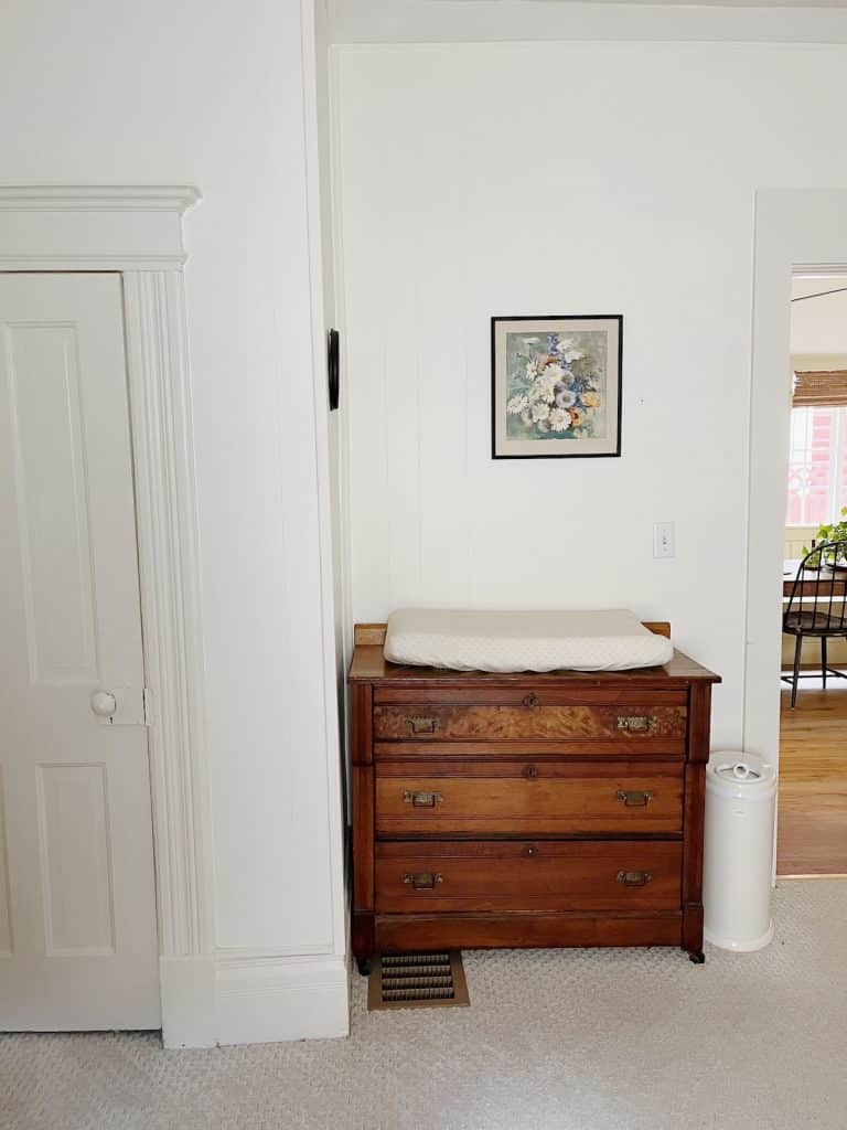 changing pad on wood dresser with floral art print hanging above