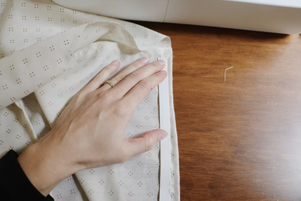 hand holding elastic over fabric on wood tablehem 