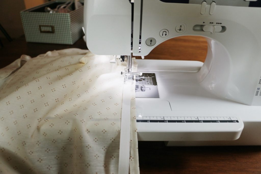 sewing machine attaching elastic to fabric on wood table